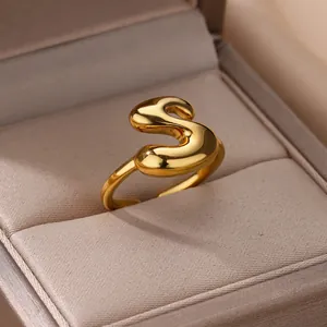 Detail van 18K vergulde bubble letter S ring op een champagne zijden juwelendoos
