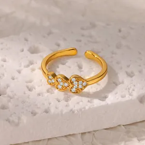 Macro shot of gold-plated triple heart ring with white zircons on a marble stone