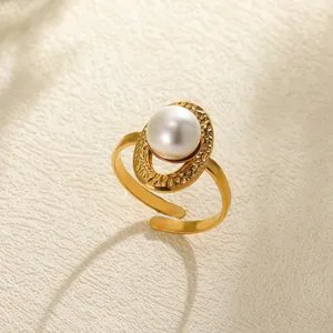 Close-up of golden geometric hollow ring with white faux pearl and hammered metal texture