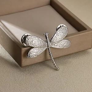 Vintage textured dragonfly brooch in silver titanium steel on a luxury jewelry box