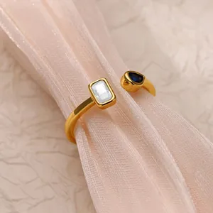 Detail of golden adjustable ring with rectangle zircon and blue teardrop gem on silk