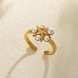 Detail shot of a golden starfish open ring featuring five elegant white pearls on its arms