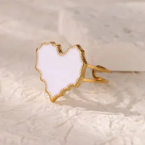 Macro shot of gold stainless steel heart ring with white enamel inlay and beaded edges