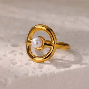 Macro shot of gold hollow geometric ring featuring a glossy pearl on a stone base