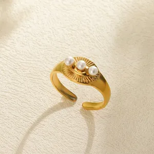Detail of gold vintage open ring with sunray texture and three white pearls