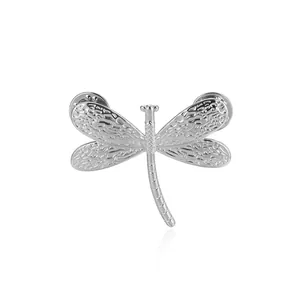 Macro shot of silver dragonfly brooch featuring textured wings and dual butterfly clasps