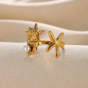 Adjustable gold starfish ring with white pearl detail on textured wavy background