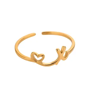 Détail d'une bague ouverte dorée avec cœur évidé et design minimaliste en forme de lettre Y