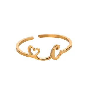 Gros plan d'une bague dorée en acier inoxydable avec cœur ajouré et détail de la lettre C