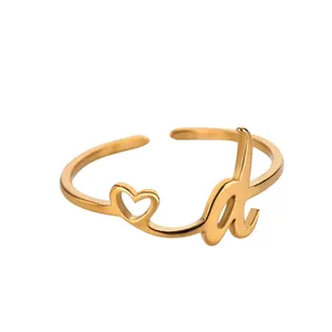 Détail d'une bague coeur dorée réglable ornée d'une élégante lettre a en cursive fine