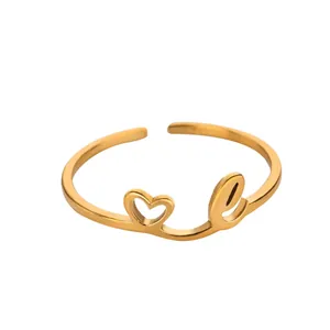Détail de la bague ajustable dorée avec un motif cœur évidé et la lettre cursive e