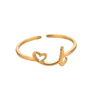 Détail d'une bague ajustable en acier doré avec découpes de cœur et lettre élégante