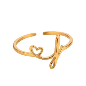 Détail macro d'une bague dorée en acier inoxydable avec cœur découpé et lettre cursive J