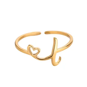 Détail d'une bague ouverte dorée avec un cœur évidé et un design de lettre L cursive