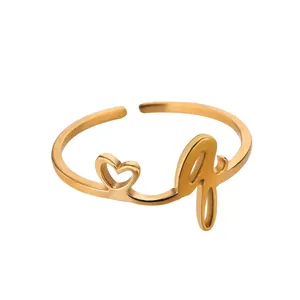 Détail d'une bague dorée ajustable avec un cœur évidé minimaliste et la lettre q gravée