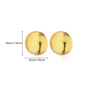 Detail view of 30mm gold-plated titanium steel ball earrings with ribbed metal texture
