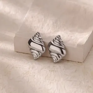 Macro detail of high-polish silver camellia flower earrings with elegant spiral petals