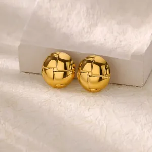 Detailed shot of golden hollow bead earrings with camellia-inspired woven texture on white stone