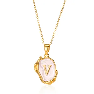 Detail of 18K gold letter V necklace with pink enamel on a molten textured oval pendant