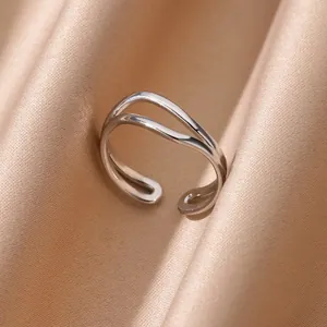 Dettaglio ravvicinato di un anello aperto a doppia onda in argento su seta color champagne