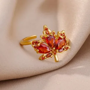 Adjustable red maple leaf ring with cubic zirconia on champagne silk background