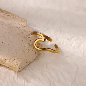Detail of minimalist 18K gold plated stainless steel ring on beige travertine stone