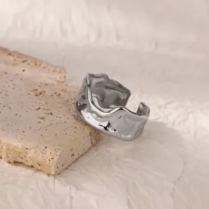 Detailed close-up of a silver irregular wave ring on a natural travertine stone surface