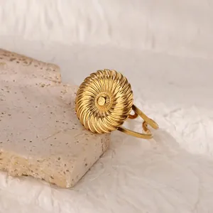 Macro shot of gold 18K plated stainless steel ring with spiral texture on stone surface