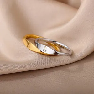 Macro shot of gold and silver initial S rings on champagne satin luxury background