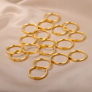 Minimalist gold stainless steel initial rings collection for men and women on beige silk