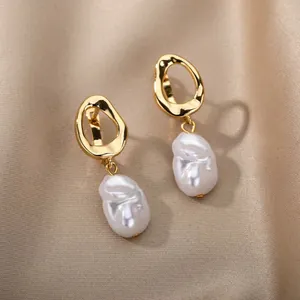 Detail of baroque pearl drop earrings with hammered gold finish on silk background