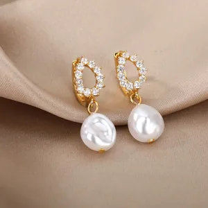 Detailed close-up of bow-style golden earrings with baroque pearls and zircon on silk