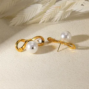 Détail des boucles d'oreilles nœud doré avec perle blanche et zircon en forme de cœur