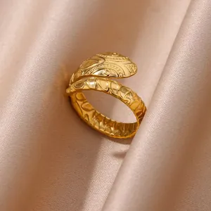 Detailed macro shot of a golden snake ring with scales on a champagne silk background