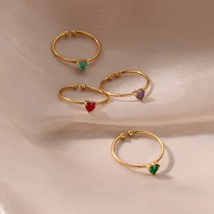 Detail of four 18K gold plated heart birthstone rings on beige silk fabric