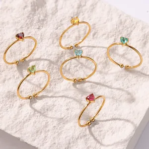 Detailed view of six gold rings with heart-shaped colorful zircons on white stone