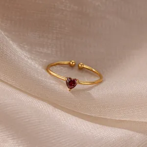 Macro shot of gold 18K plated heart-shaped red zircon ring on champagne satin fabric