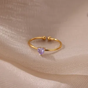 Detail of a 18K gold plated ring with a purple heart-shaped zircon on silk background