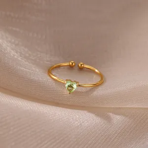 Detail of 18K gold heart-shaped light green zircon ring on champagne silk fabric