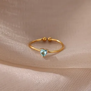 Close-up of gold adjustable heart ring with light blue zircon on beige silk fabric
