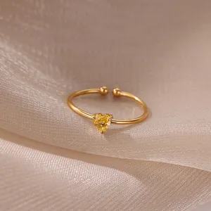 Detail view of adjustable golden ring with a yellow heart zircon on silk fabric