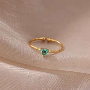 Close-up of gold plated ring featuring a green heart-shaped zircon on silk fabric