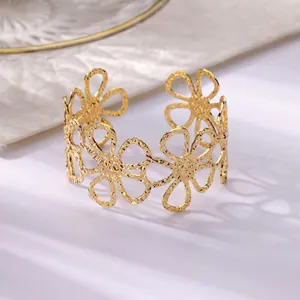 Golden open cuff bracelet with hollow floral design and hammered metal texture finish