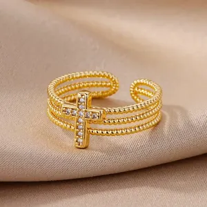 Detalle de anillo dorado de tres capas con cruz de circonitas sobre fondo de seda suave