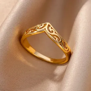 Primer plano de anillo en V dorado con intrincados relieves clásicos sobre seda champán