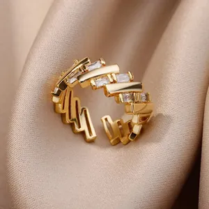 Macro de un anillo dorado texturizado con circonitas rectangulares sobre satén champán