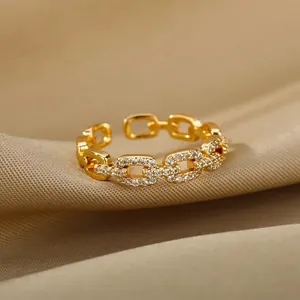 Primer plano de un anillo de cadena dorado con circones sobre seda beige