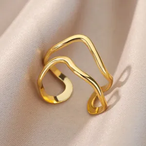 Detalle de anillo de doble capa ondulada en acero inoxidable dorado sobre seda