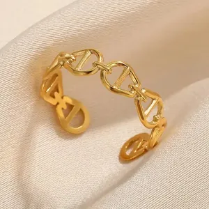 Detalle de anillo de eslabones de ancla en acero dorado sobre fondo seda beige