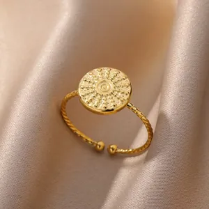 Anillo ajustable dorado con disco solar y banda trenzada sobre seda color champán